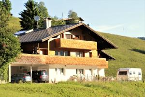 uma casa numa colina com carros estacionados na frente em Sonnennest em Hirschegg