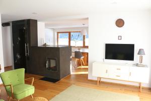 uma sala de estar com uma televisão e uma cadeira verde em Sonnennest em Hirschegg