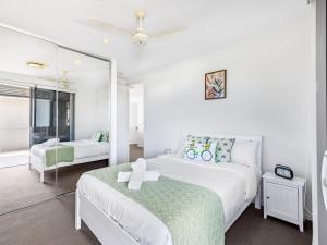 a white bedroom with two beds and a mirror at Spacious 3BR Retreat w Lake view Varsity Lakes in Gold Coast