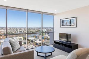 a living room with a couch and a tv at Amazing 2BR delicate Apt, 1min to train station in Brisbane