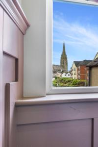 une fenêtre ouverte avec vue sur une église dans l'établissement Hestia House, à Derry Londonderry