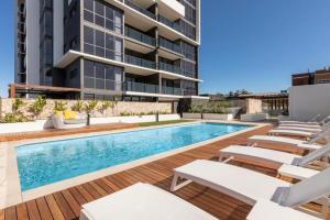 a swimming pool with lounge chairs and a building at Amazing 2BR delicate Apt, 1min to train station in Brisbane
