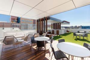 - un balcon avec des tables et des chaises dans un bâtiment dans l'établissement Amazing 2BR delicate Apt, 1min to train station, à Brisbane