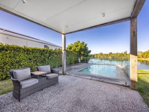 an outdoor patio with chairs and a swimming pool at Luxurious 4BR Waterfront Retreat in Mermaid Waters in Gold Coast