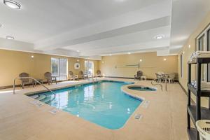 una piscina en una habitación de hotel con sillas y mesas en Comfort Suites Brunswick, en Brunswick