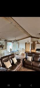 a living room with leather furniture and a dining room at Badgers rest lodge in Kinlet