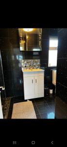a black tiled bathroom with a white cabinet and a sink at Badgers rest lodge in Kinlet