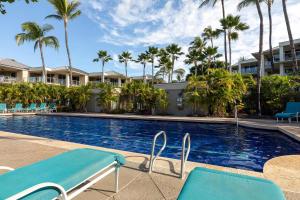 einen Pool mit blauen Stühlen und Palmen in der Unterkunft Vista Waikoloa A104 in Waikoloa