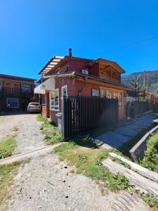 a house with a fence in front of it at Hostal Robinson in Puerto Puyuhuapi