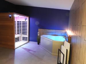 een grote badkamer met een bad in een blauwe muur bij Hors du temps in Ourt