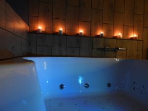 uma banheira branca na casa de banho com velas em Hors du temps em Ourt