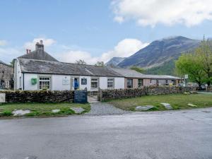 a building with a stone wall next to a mountain at 3 Bed in Buttermere 82775 in Buttermere