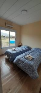 2 camas en un dormitorio con ventana grande en Buena Vista en San Andrés de las Sierras