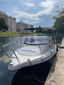 a white boat tied to a dock in the water at Apartament MotłEwa in Gdańsk