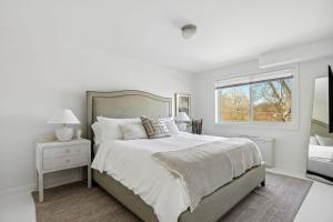 a white bedroom with a large bed and a window at Crystal City Boutique Flats 2BR - Free Parking 204 in Arlington