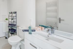 a white bathroom with a toilet and a sink at 44m² - Cosy - Neuf - Parking in Massy