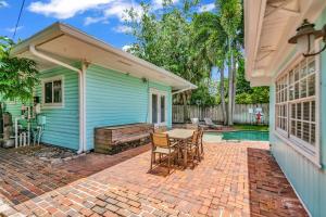 een blauw huis met een patio met een tafel en stoelen bij Zach's Tropical Pool House in Fort Lauderdale