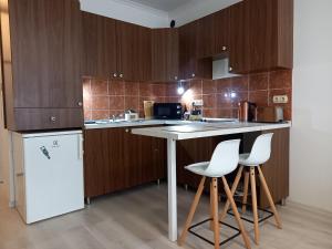 a kitchen with wooden cabinets and a counter with stools at Mimi Apartman in Szeged