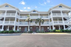 a large white building with palm trees in front of it at Arbor Trace #811 condo in North Myrtle Beach