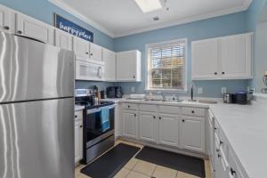 a kitchen with white cabinets and a refrigerator at Arbor Trace #811 condo in North Myrtle Beach