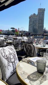 a group of tables and chairs with a castle in the background at Tour de la chaine, vieux port, Grand Appartement in La Rochelle
