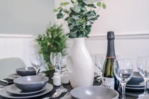 a table with a vase and plates and wine glasses at Stylish House in Manchester Sleeps7 Wifi & Parking by PureStay in Manchester