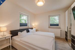 ヘリングスドルフにあるVilla Doris Whg 2 Morgensonneのベッドルーム1室(白いベッド1台、窓2つ付)