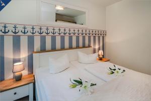 ヘリングスドルフにあるVilla Doris Whg 4 Sonnenblickのベッドルーム1室(花が咲く白いベッド1台付)