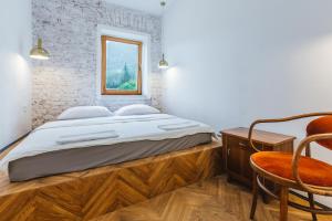 a bedroom with a bed and a chair and a window at 2nd Station Hostel in Bled