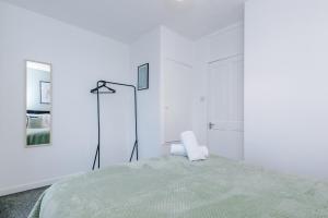 a white bedroom with a bed and a chair at Stylish House in Manchester Sleeps7 Wifi & Parking by PureStay in Manchester