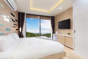 a bedroom with a large bed and a large window at Appartements avec piscine in Rawai Beach
