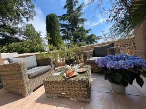 un patio con sillas de mimbre, una mesa y flores en Carolienne en Vallauris