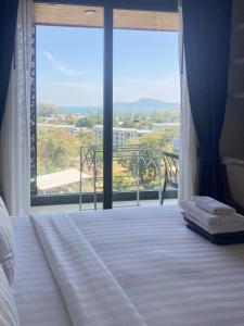 a bedroom with a bed and a large window at Appartements avec piscine in Rawai Beach