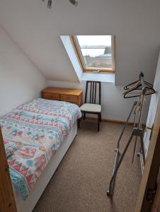 1 dormitorio con cama, ventana y trípode en Tangles & Kelpie en Burray Village