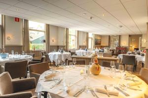 une salle à manger avec tables et chaises et nappes blanches dans l'établissement De Klomp Charme Hotel & Restaurant, à Vilsteren