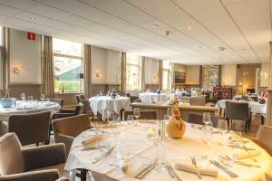 a dining room with tables and chairs with white tablecloths at De Klomp Charme Hotel & Restaurant in Vilsteren