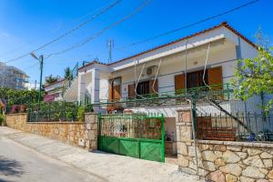 a house with a green gate on a stone wall at Cozy Apartments Downtown in Ksamil