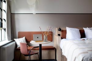 een slaapkamer met een bed en een tafel met een laptop bij Bob W Østerbro Copenhagen in Kopenhagen