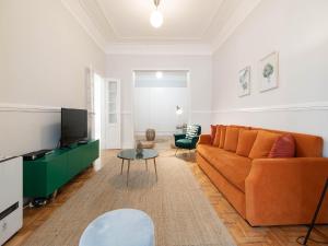 sala de estar con sofá naranja y TV en Akicity Lisboa Iris en Lisboa