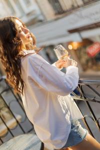a woman sitting on a fence holding a glass at My Luxury Downtown Vibe Suites in Rethymno