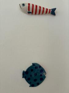 two fish on a white wall next to a blue object at Casa Civetta in Stromboli