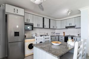 a kitchen with a stainless steel refrigerator and white cabinets at Chakas Cove 38 in Ballito