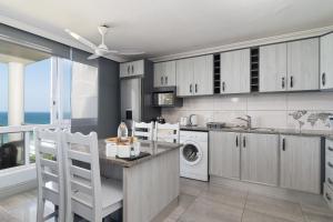 a kitchen with white cabinets and a washer and dryer at Chakas Cove 38 in Ballito