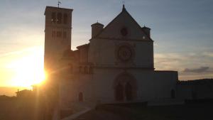 a church with the sun setting behind it at LE DIMORE ARCANGELO Giuseppe in Assisi
