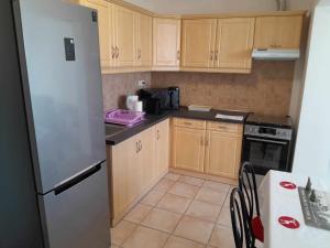 a kitchen with wooden cabinets and a white refrigerator at Rózsa Apartman in Békéscsaba