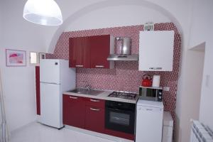 una cocina con armarios rojos y electrodomésticos blancos en Beatrice Apartment Sea View, en Vietri
