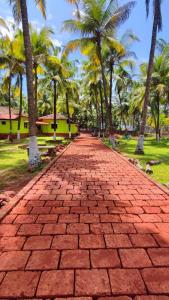 a brick road with palm trees in the background at Coco Hut , Devbaug in Malvan