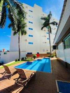 a swimming pool with two chairs and a building at SHELTON PALACE HOTEL in Paranavaí