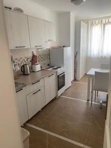 cocina con armarios blancos, mesa y encimera en Apartment Bruno NICE PLACE, en Belgrado