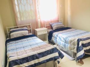 1 dormitorio con 2 camas y ventana en Villa at Grace, en Cape Coast